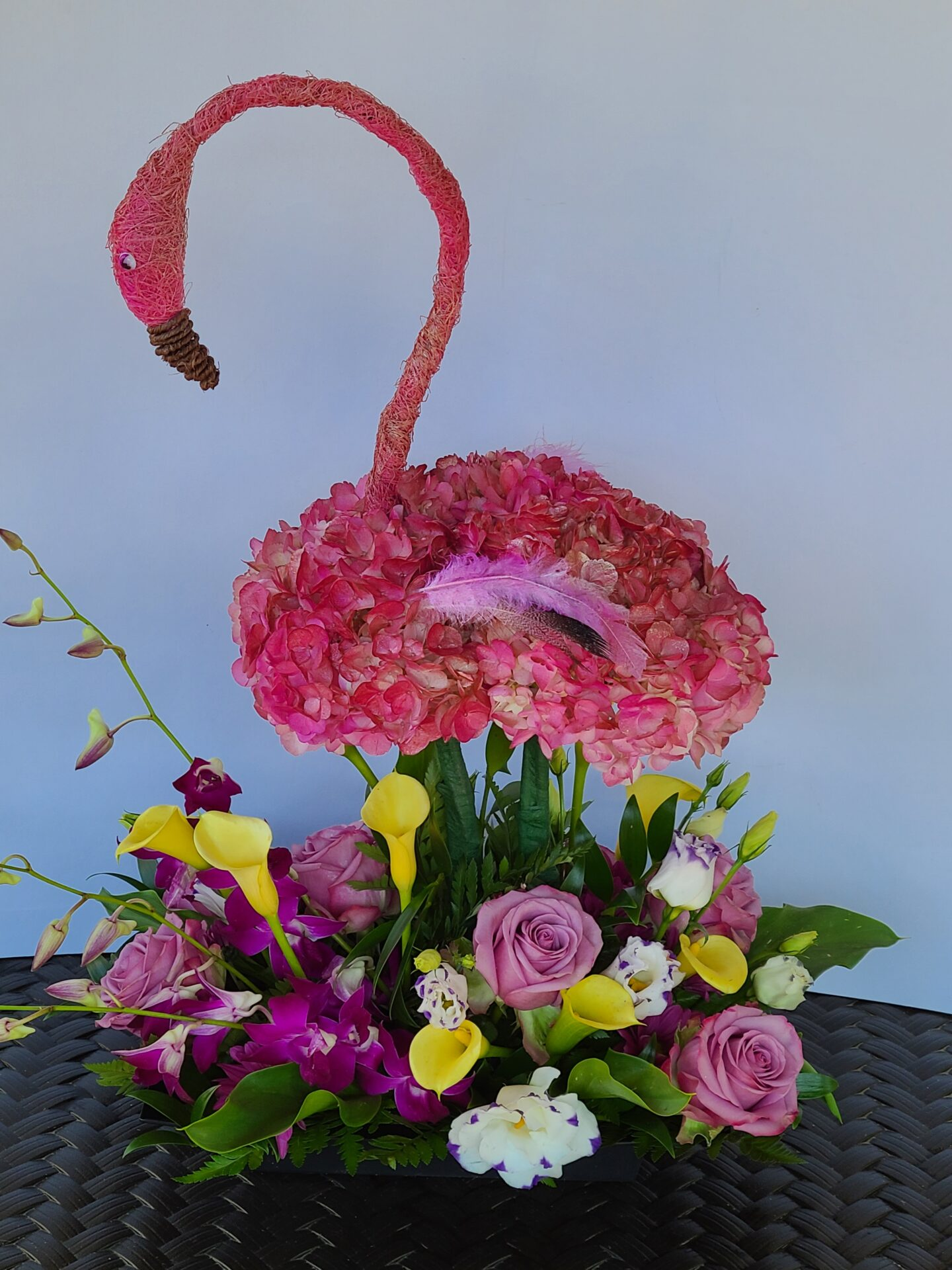 A pink flamingo made out of flowers is sitting on a table.