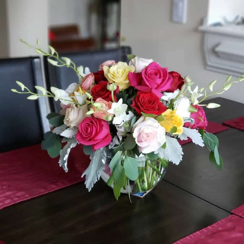A vase filled with flowers sits on a table