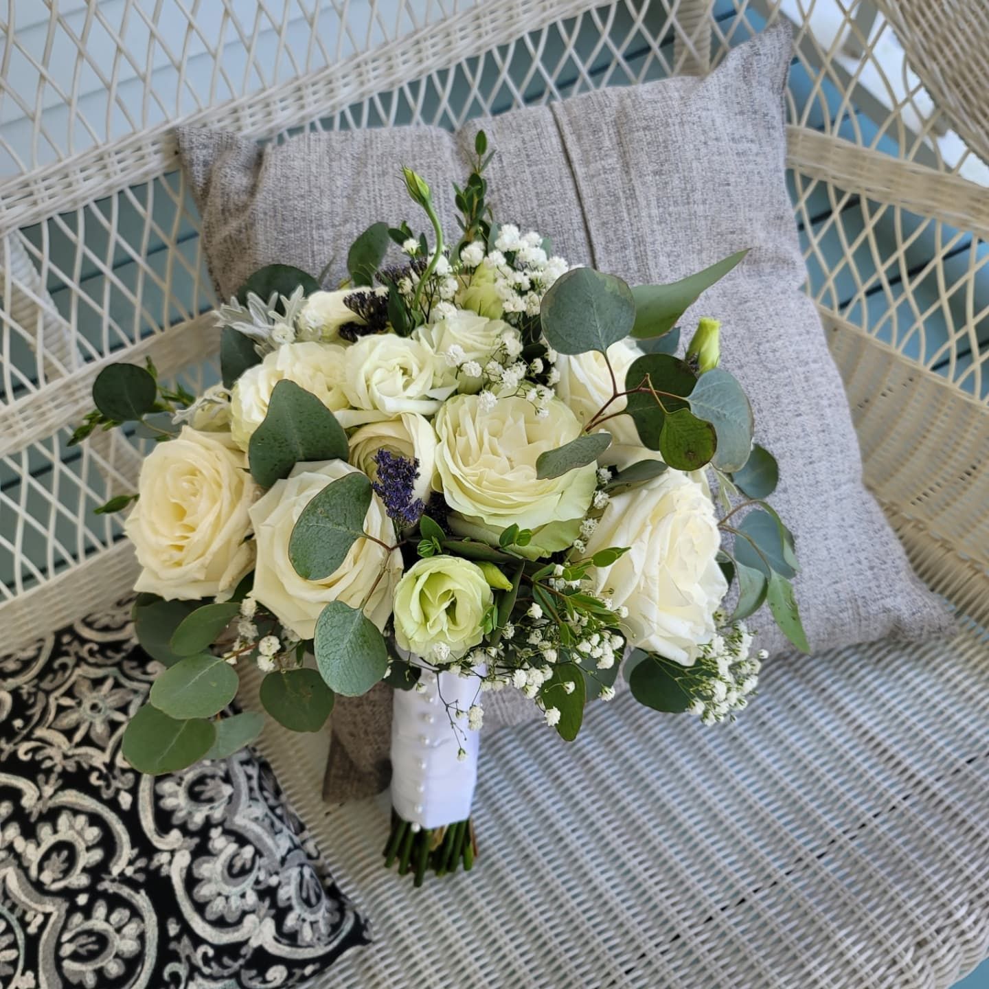 A bouquet of white flowers is sitting on a wicker chair
