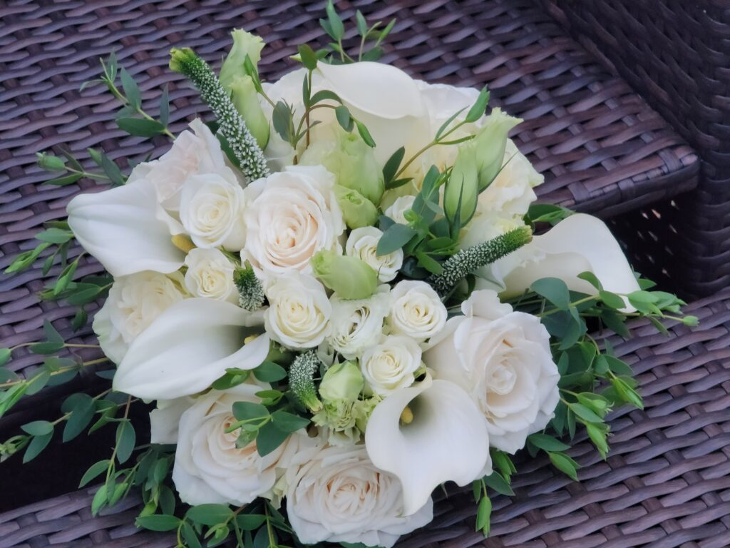 A bouquet of white flowers is sitting on a wicker table.