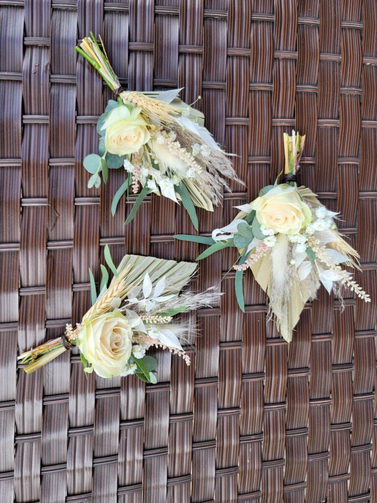 Three bouquets of flowers are sitting on a wicker table.