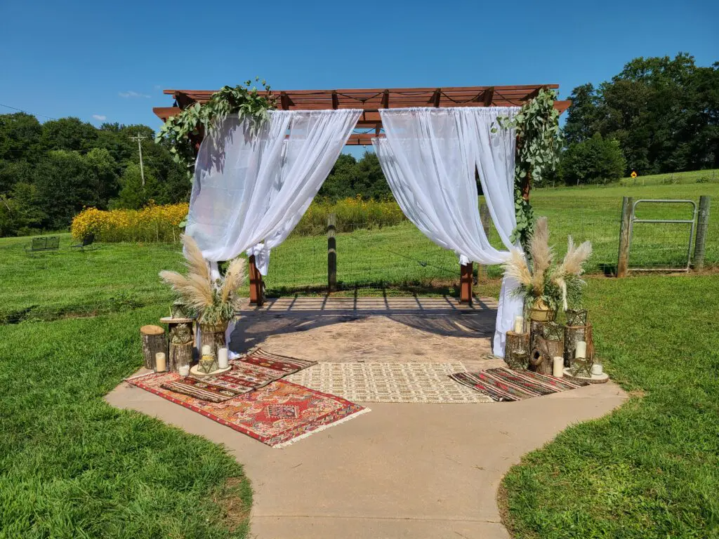 A wedding arch is sitting in the middle of a grassy field.