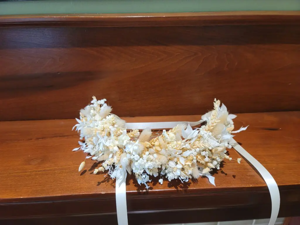 A flower crown is sitting on a wooden bench.