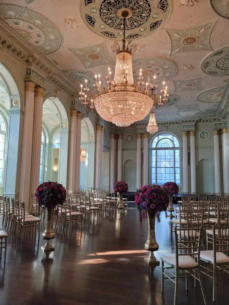 A large room filled with chairs and flowers and a chandelier.