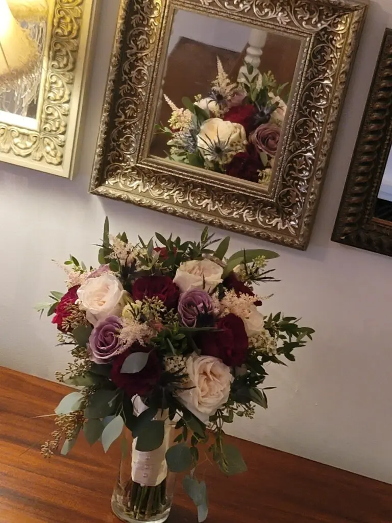 A bouquet of flowers is sitting on a table in front of a mirror.