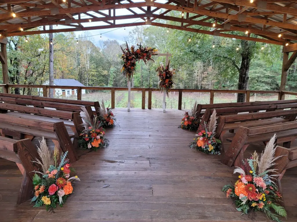 A wooden aisle decorated with flowers and benches for a wedding ceremony.