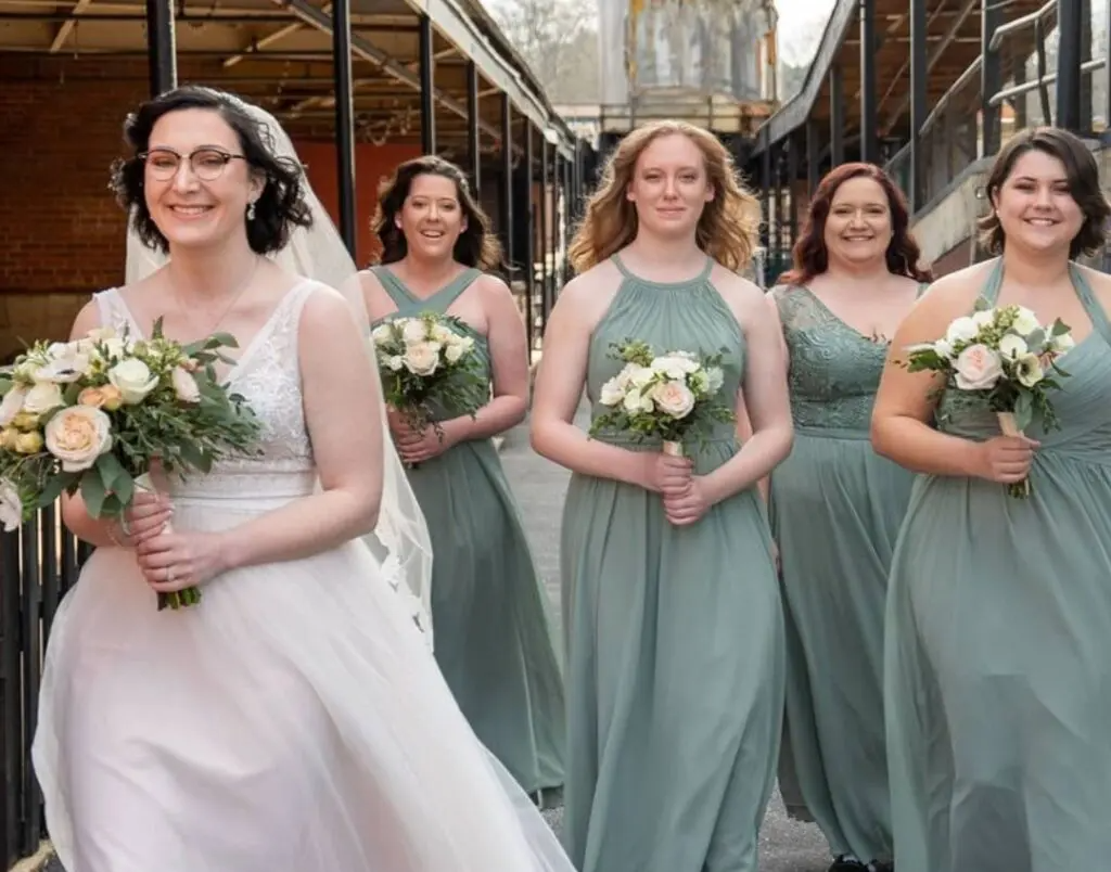 A bride and her bridesmaids are walking down a street holding bouquets of flowers.
