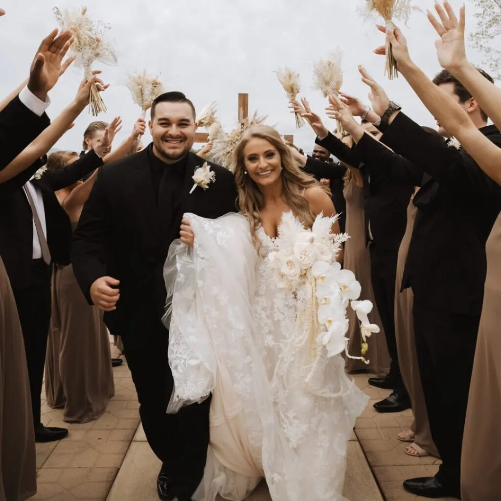 A bride and groom are walking in front of their wedding party
