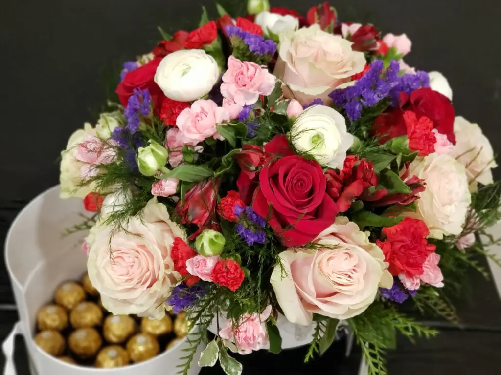 A bouquet of flowers is sitting next to a bowl of chocolates.