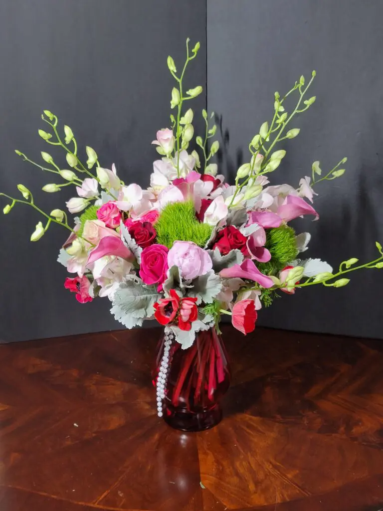 A vase filled with pink and green flowers on a wooden table