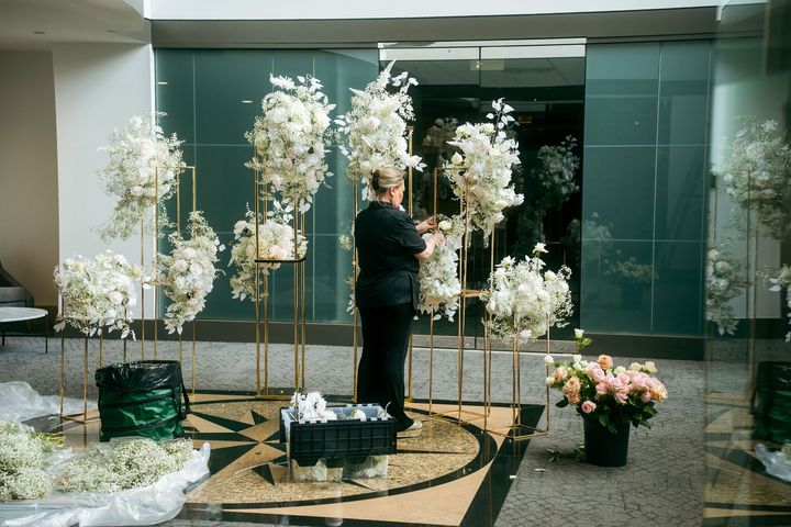 A woman is standing in front of a bunch of flowers in a room.