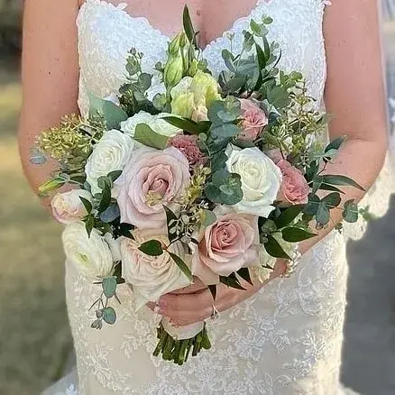 A bride in a wedding dress is holding a bouquet of flowers.