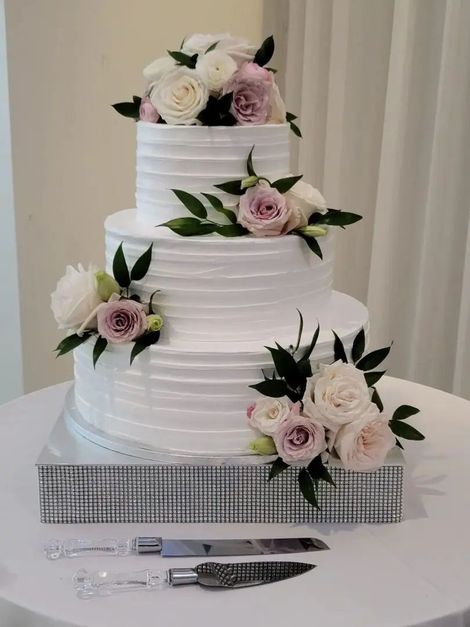 A wedding cake with flowers on top of it is on a table.