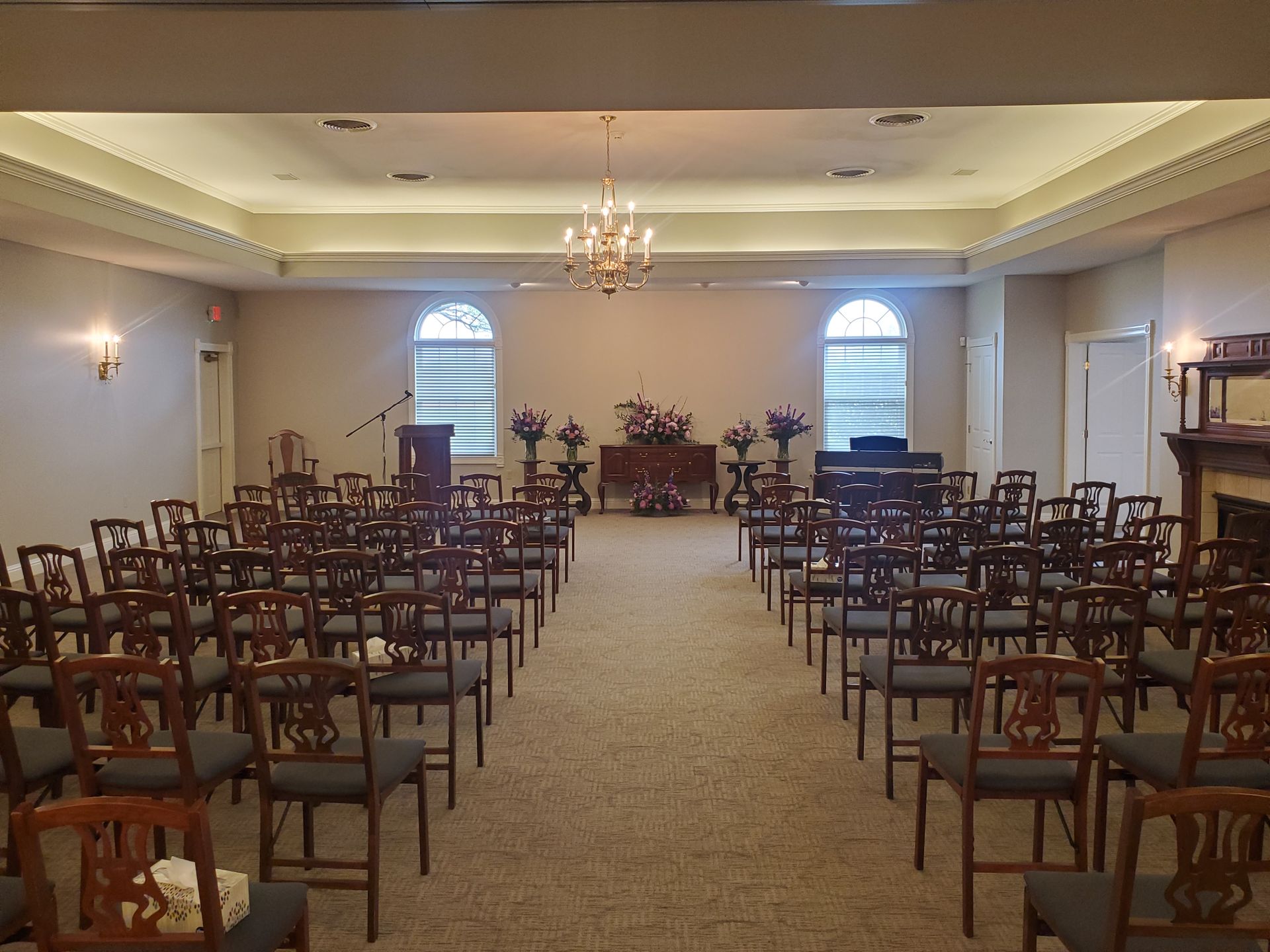 Empty banquet hall with rows of wooden chairs facing a floral altar at the far end
