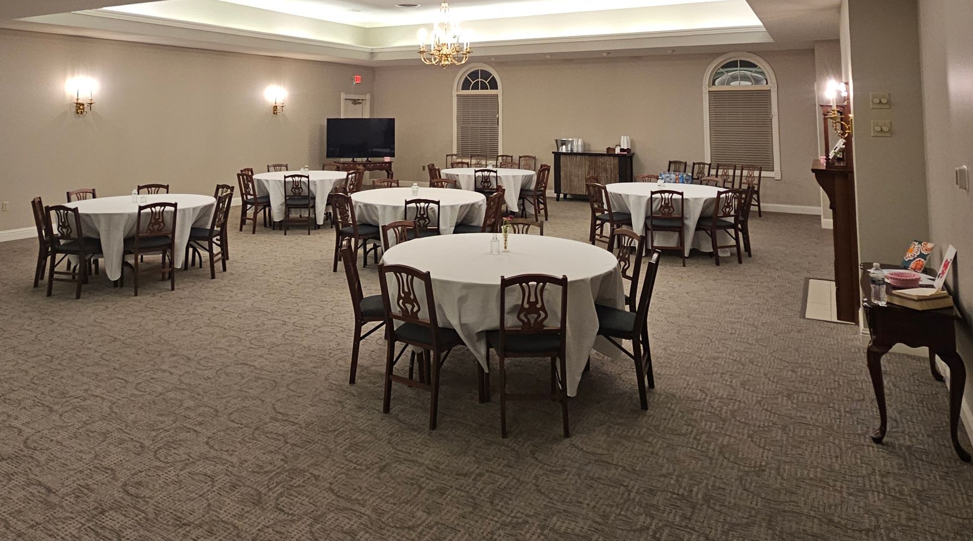 Elegant banquet hall with round tables and chairs, warmly lit and set for an event