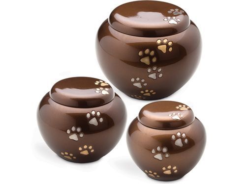 Three bronze pet cremation urns with paw print designs.