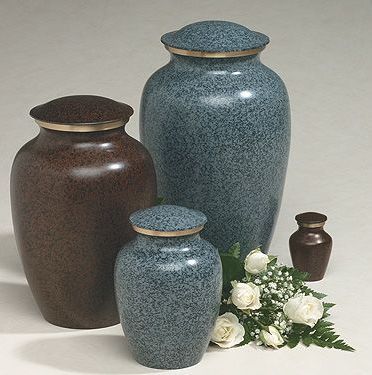 Four cremation urns of varying sizes and colors: brown, blue, and small bronze, with white flowers.