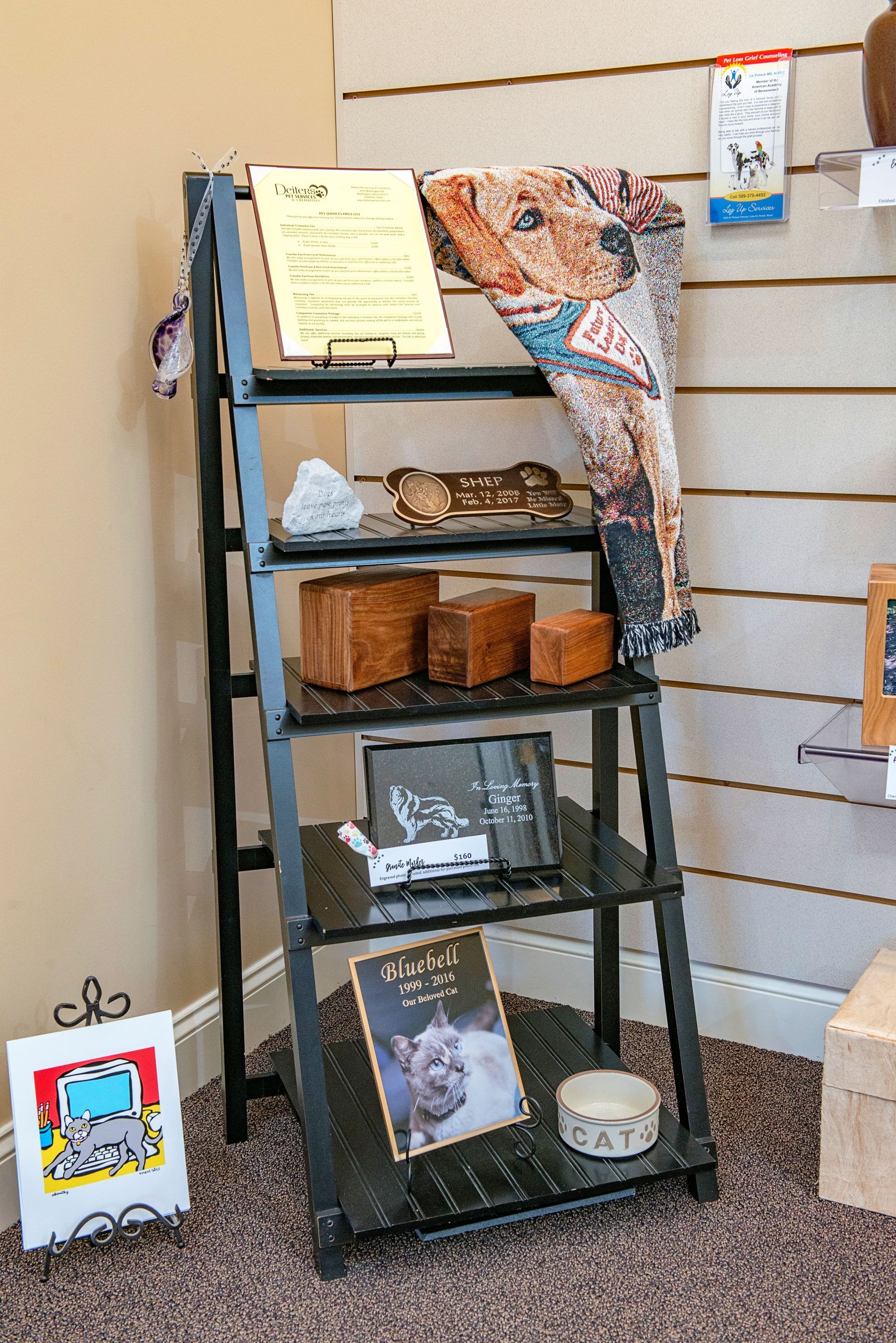 Black ladder shelf displaying various decorative items: books, boxes, and a dog-themed scarf.