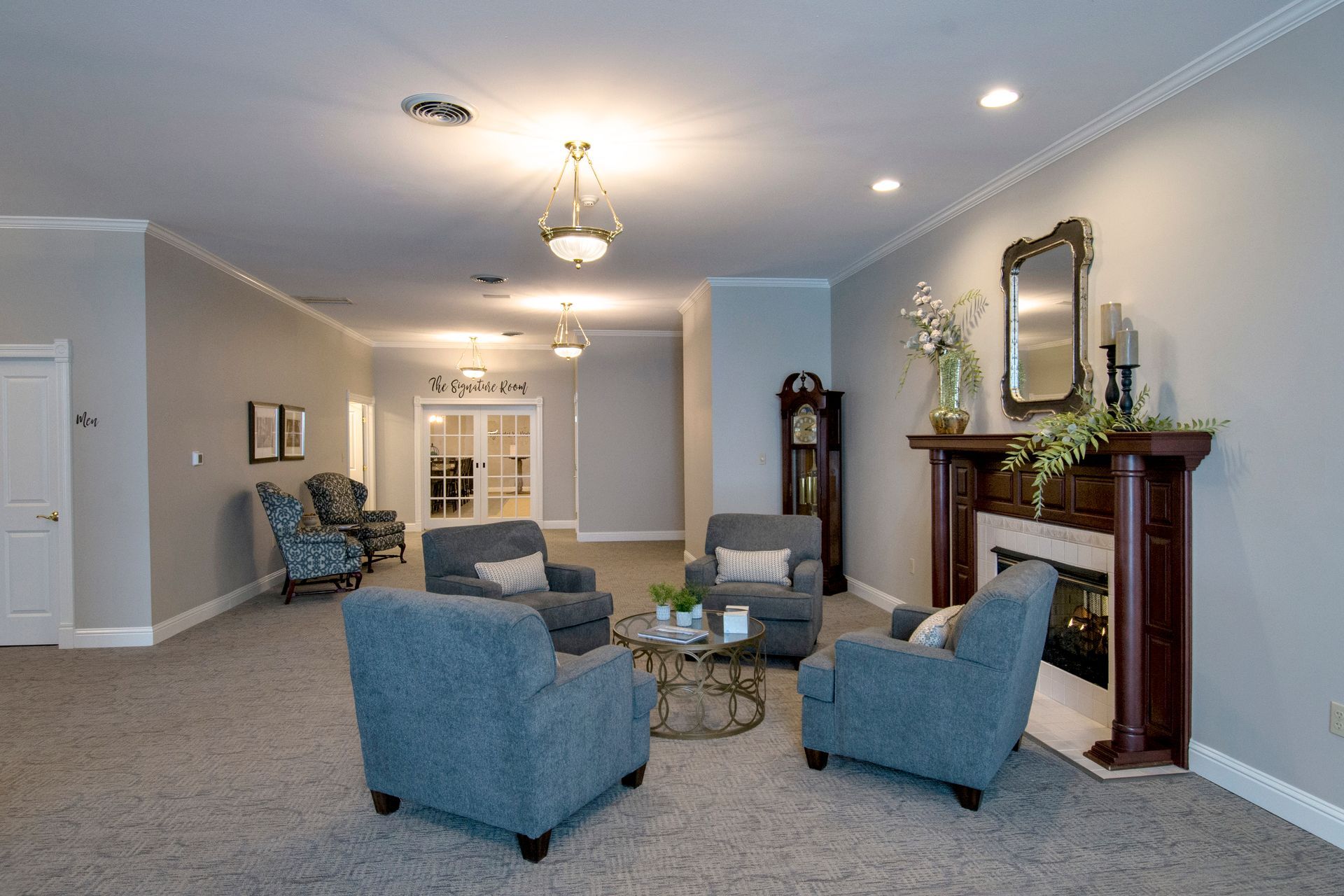 Spacious room with seating areas, fireplace, and ornate trim. Neutral colors and soft lighting.