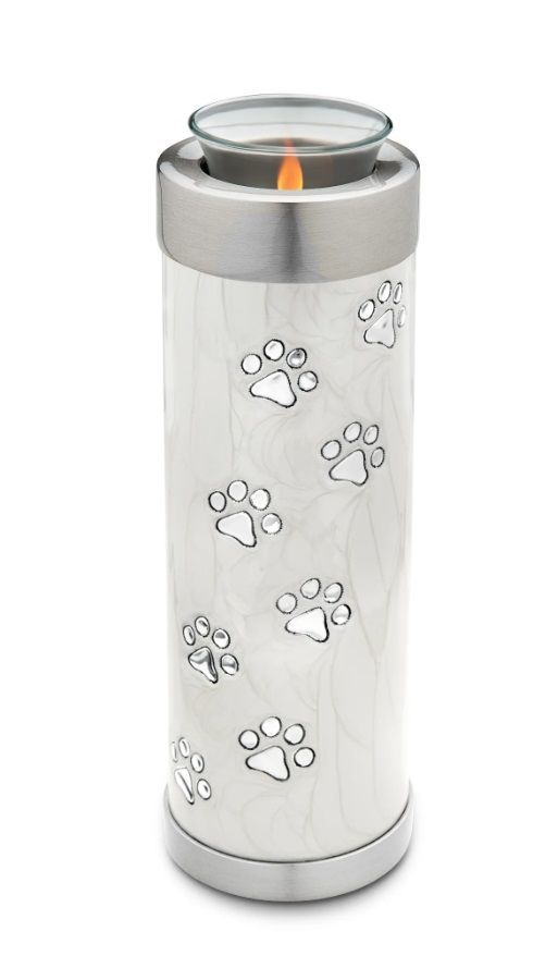 Silver pet memorial urn with paw prints and lit candle.