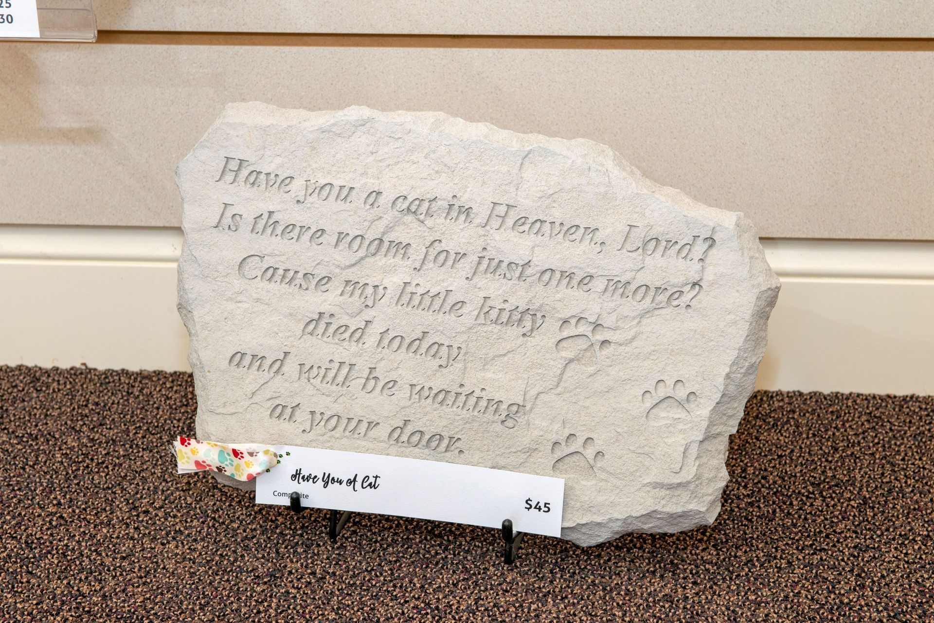Stone memorial with engraved poem for a cat, sitting on carpet.
