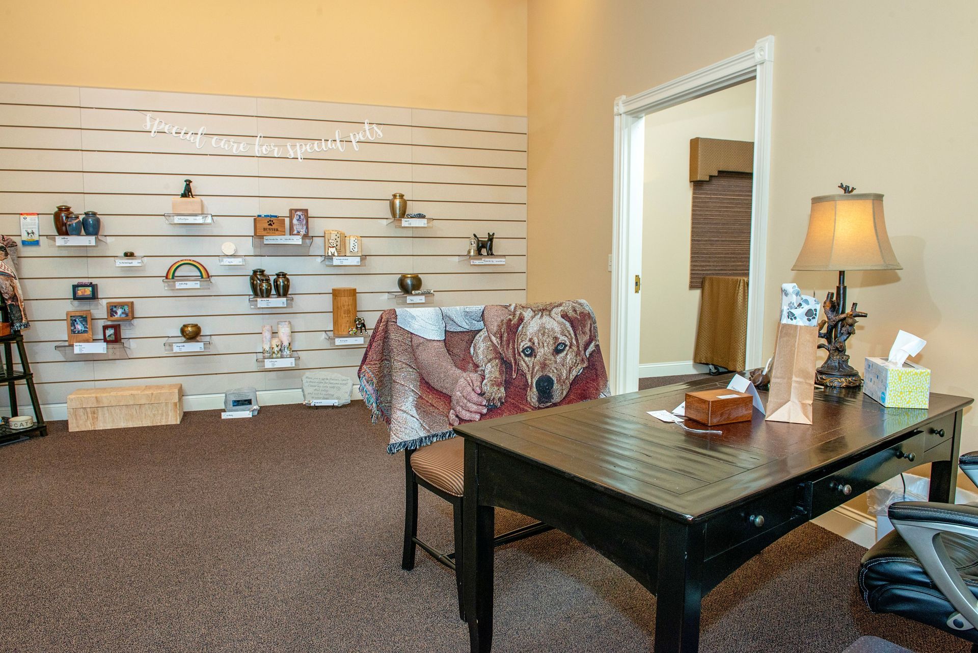 Funeral home office with displays of urns, a desk, and a dog portrait blanket.