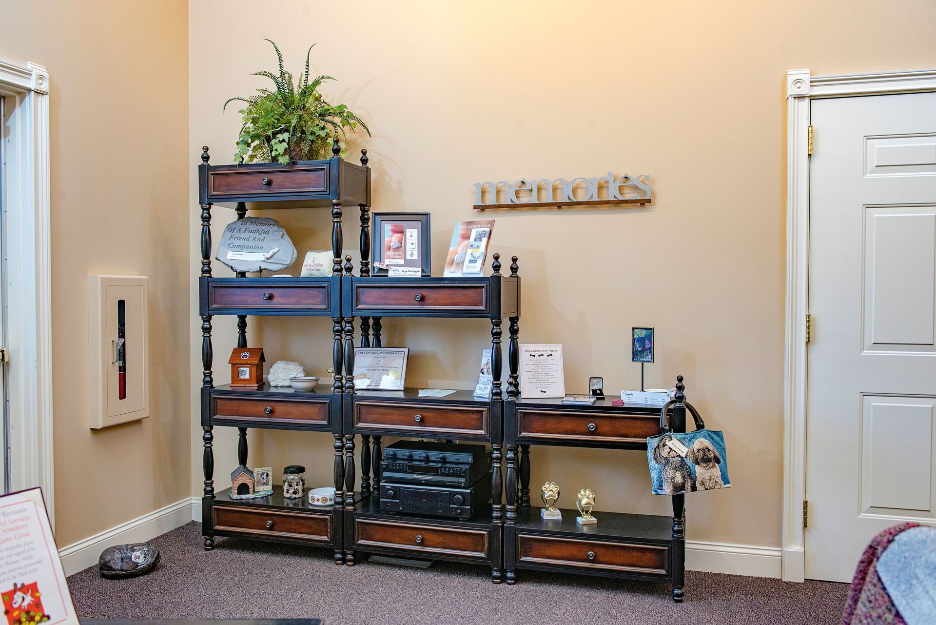 Dark wood shelving unit with various items, including plants, figurines, and electronics. Tan walls.