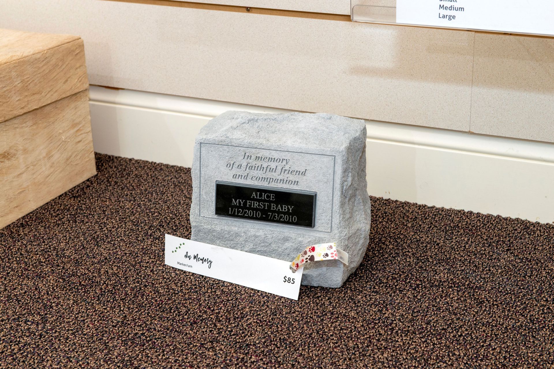 Granite memorial stone with an attached name card on a carpeted floor.
