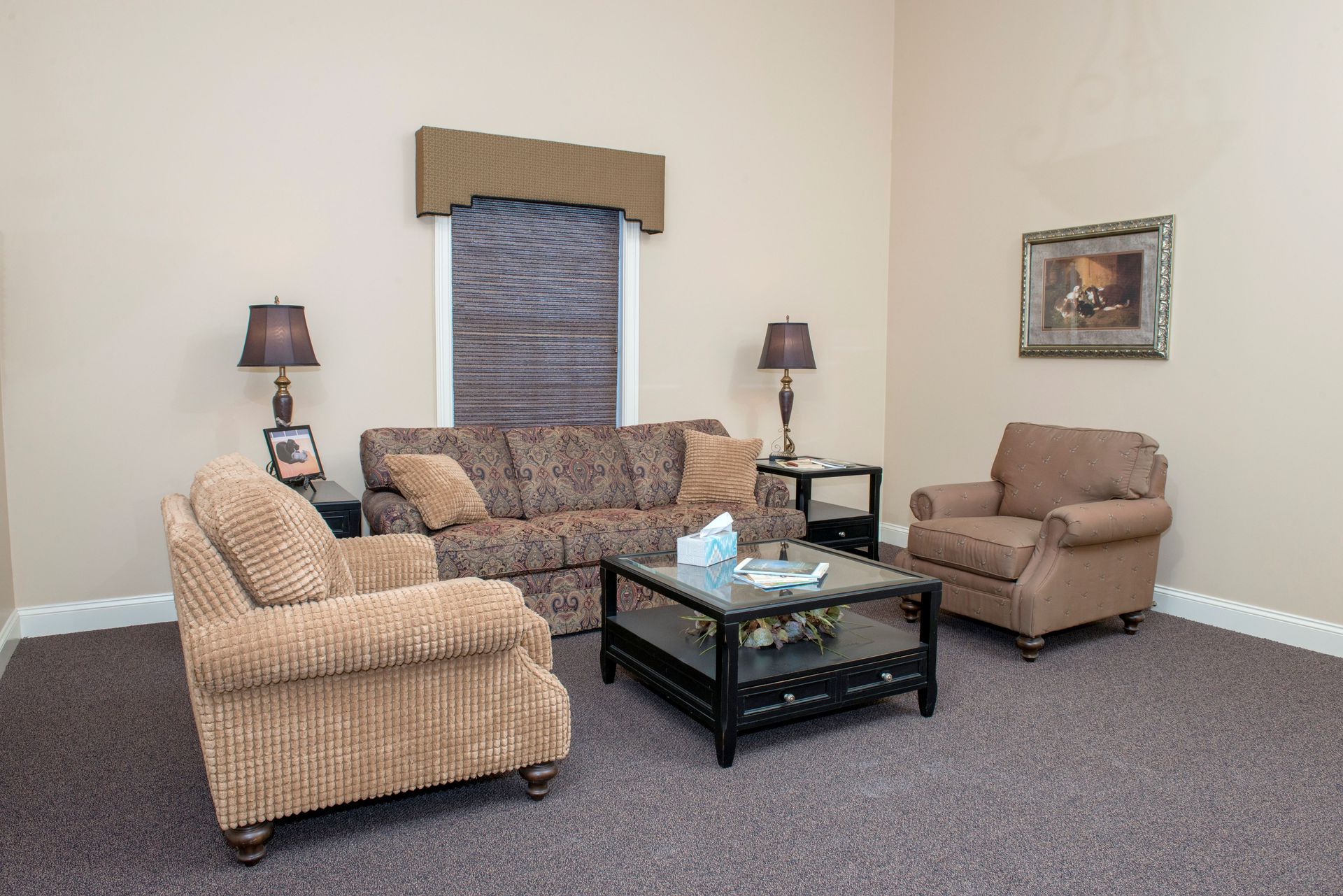 Living room with brown sofa, armchairs, coffee table, lamps, and a window.