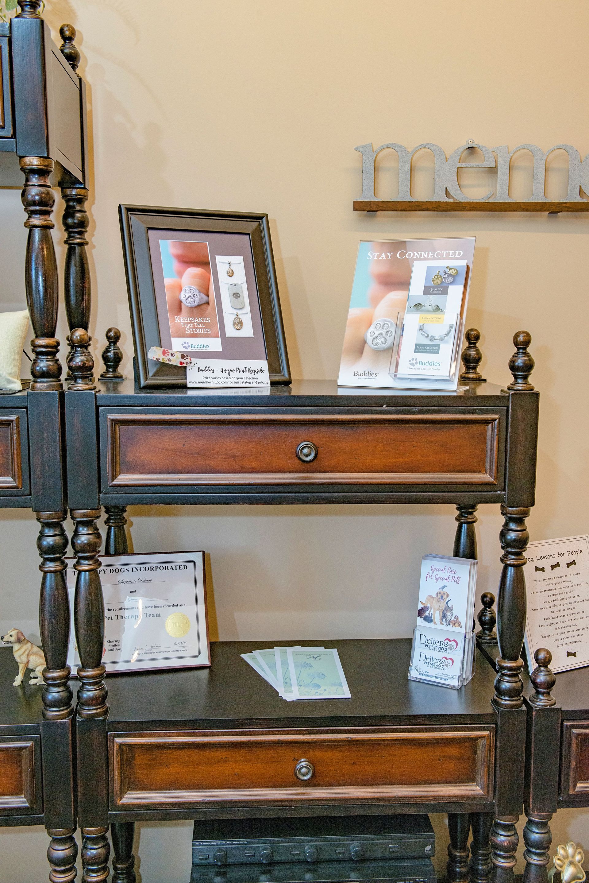 Display shelf with framed photos, brochures, and a drawer. Black and brown wood furniture.