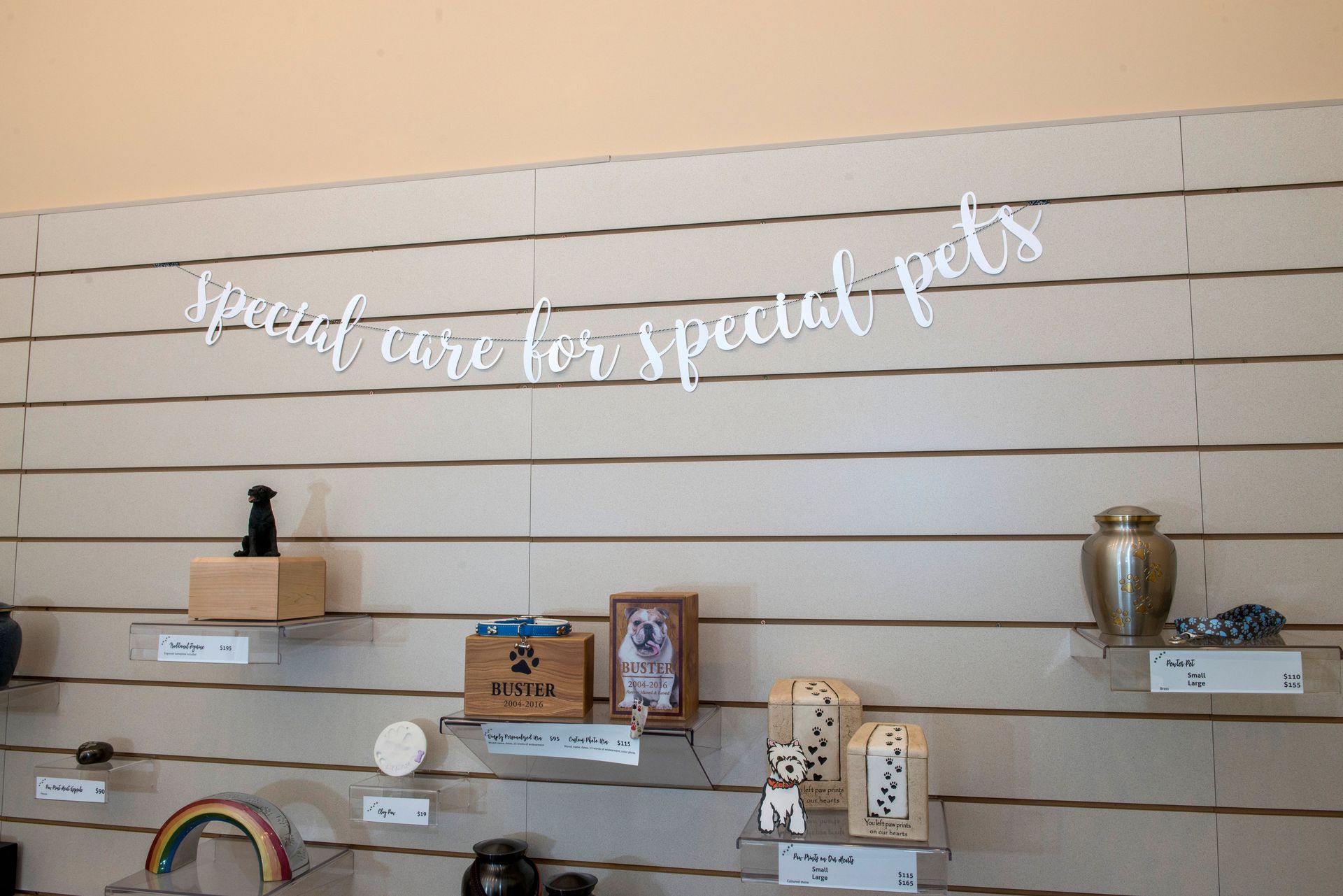 Wall display with pet urns and memorials, sign reads 