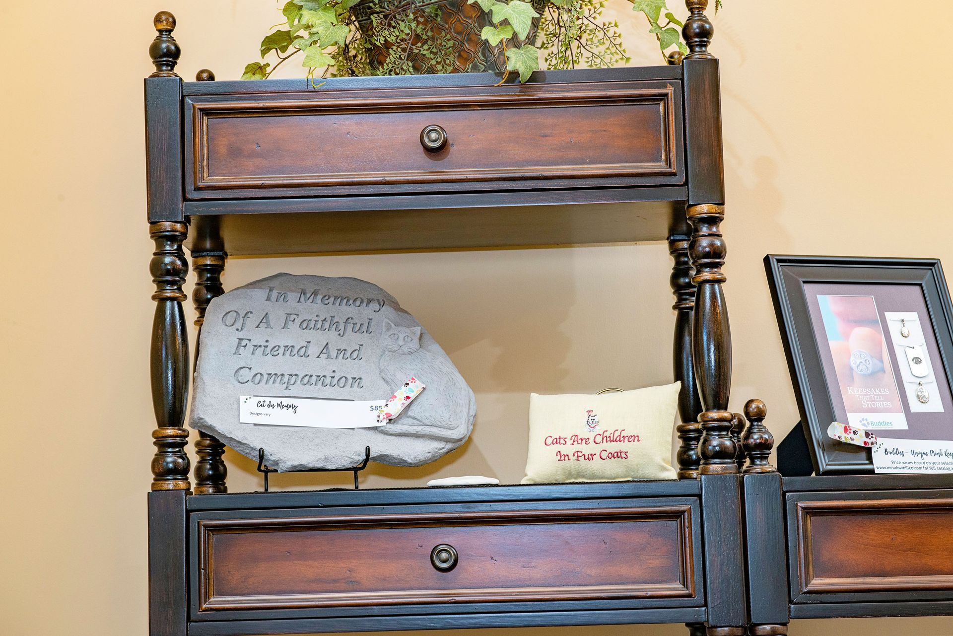 Dark wood display shelf with a memorial stone and framed items.