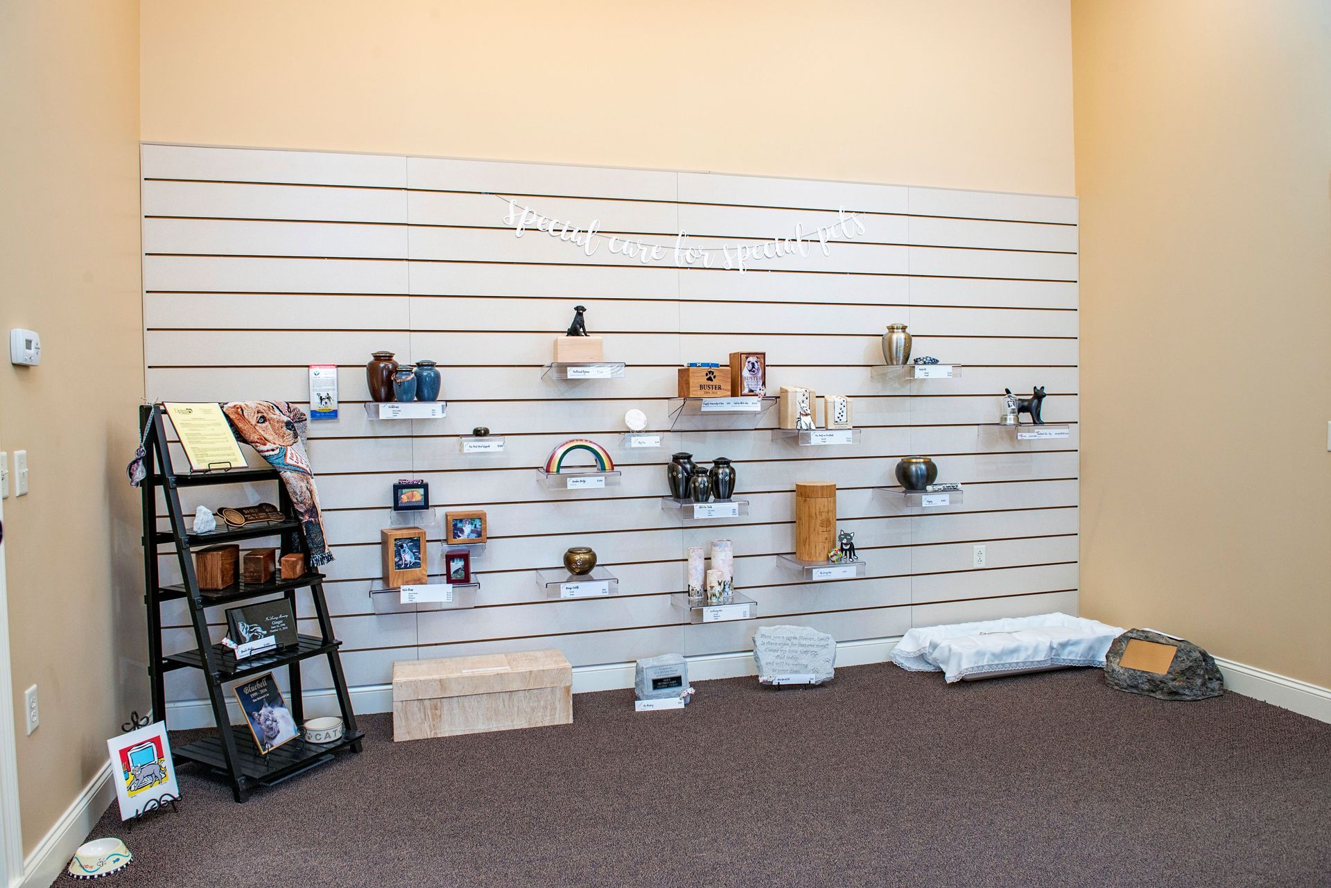 Display of urns and keepsakes on a wall and shelves in a room with carpet.