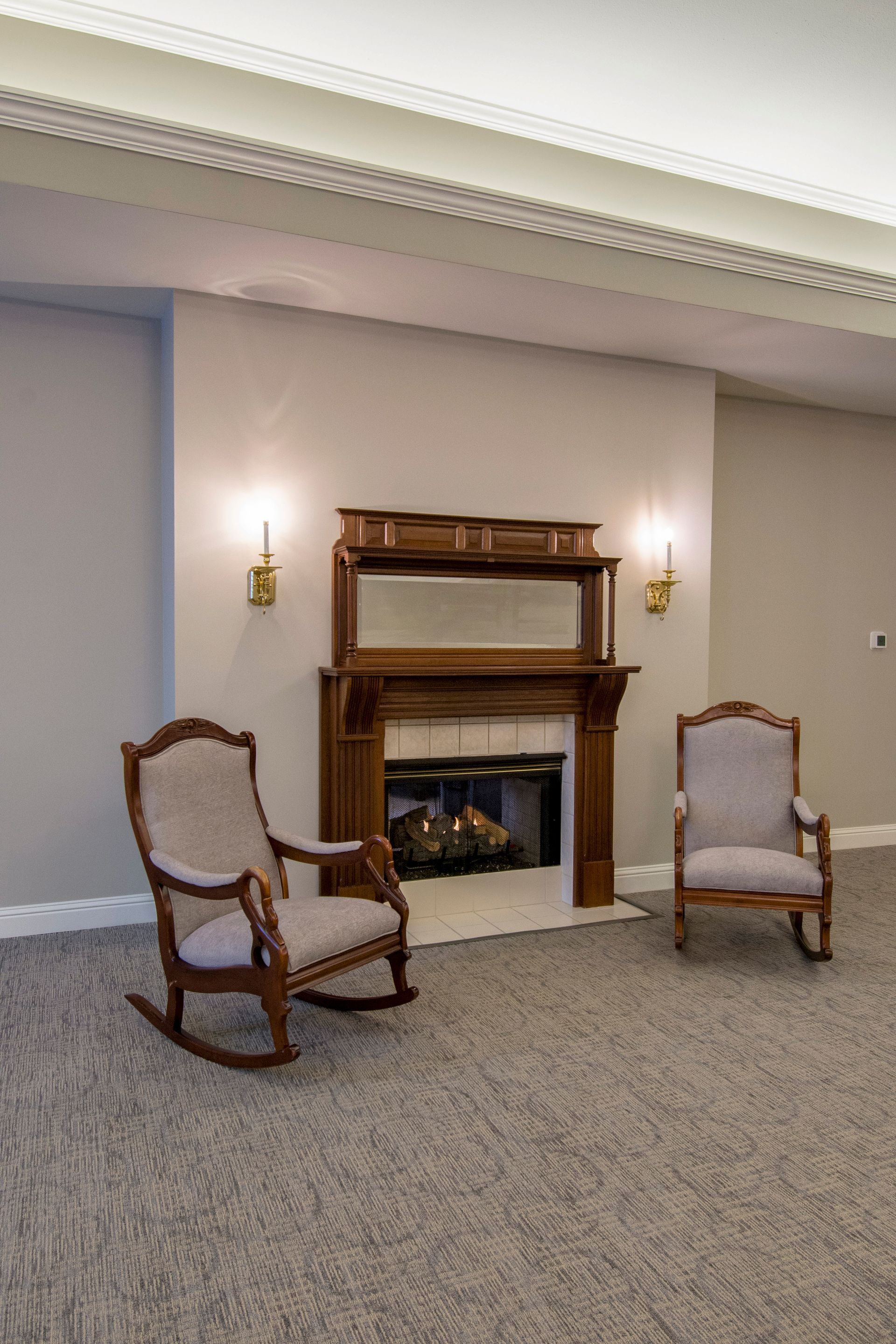 Fireplace with two rocking chairs in a room with neutral walls and carpet.