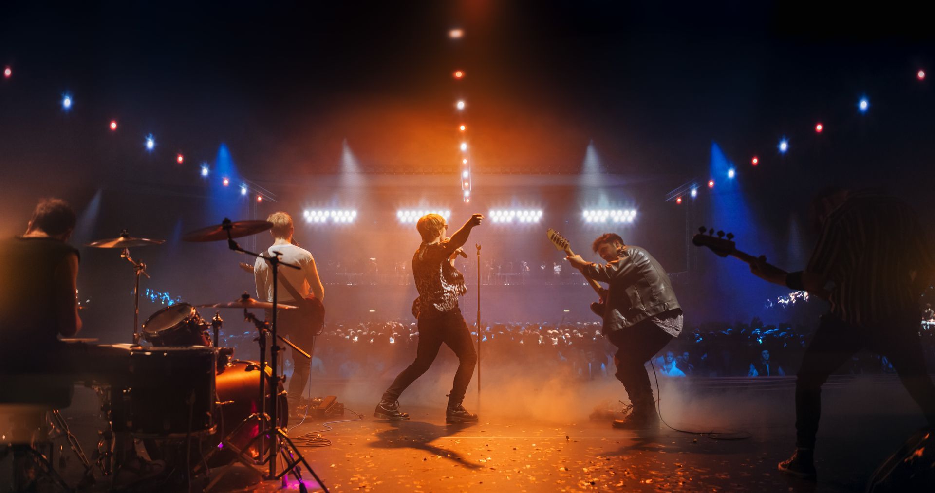 Eine Rockband tritt auf einer verrauchten Bühne mit leuchtend orangefarbenen und blauen Lichtern auf