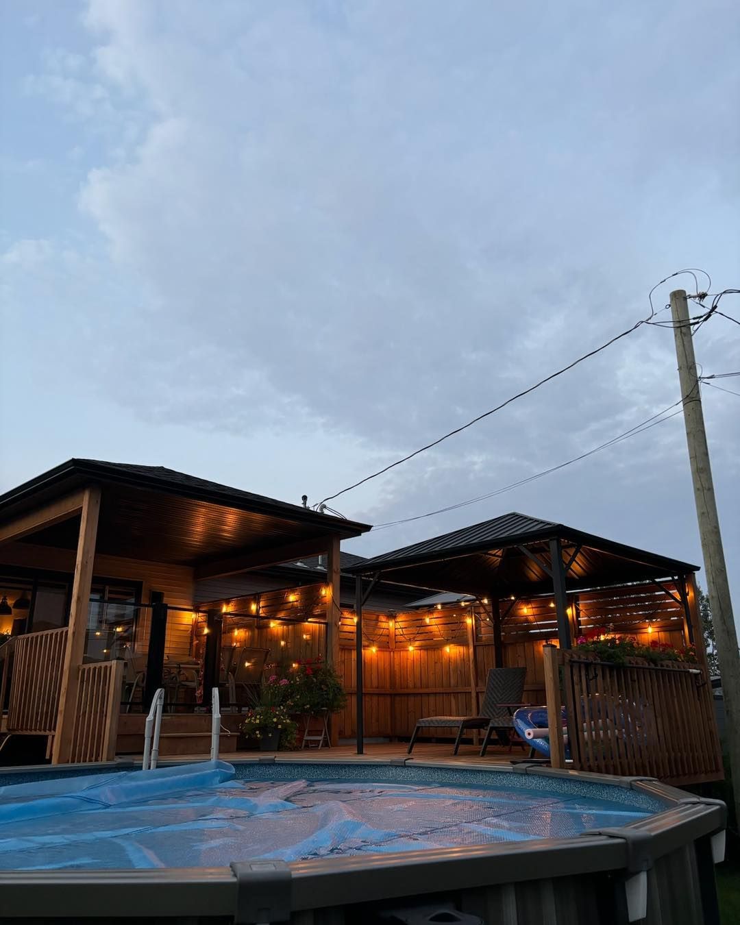 Une grande piscine est située devant une maison avec un gazebo.
