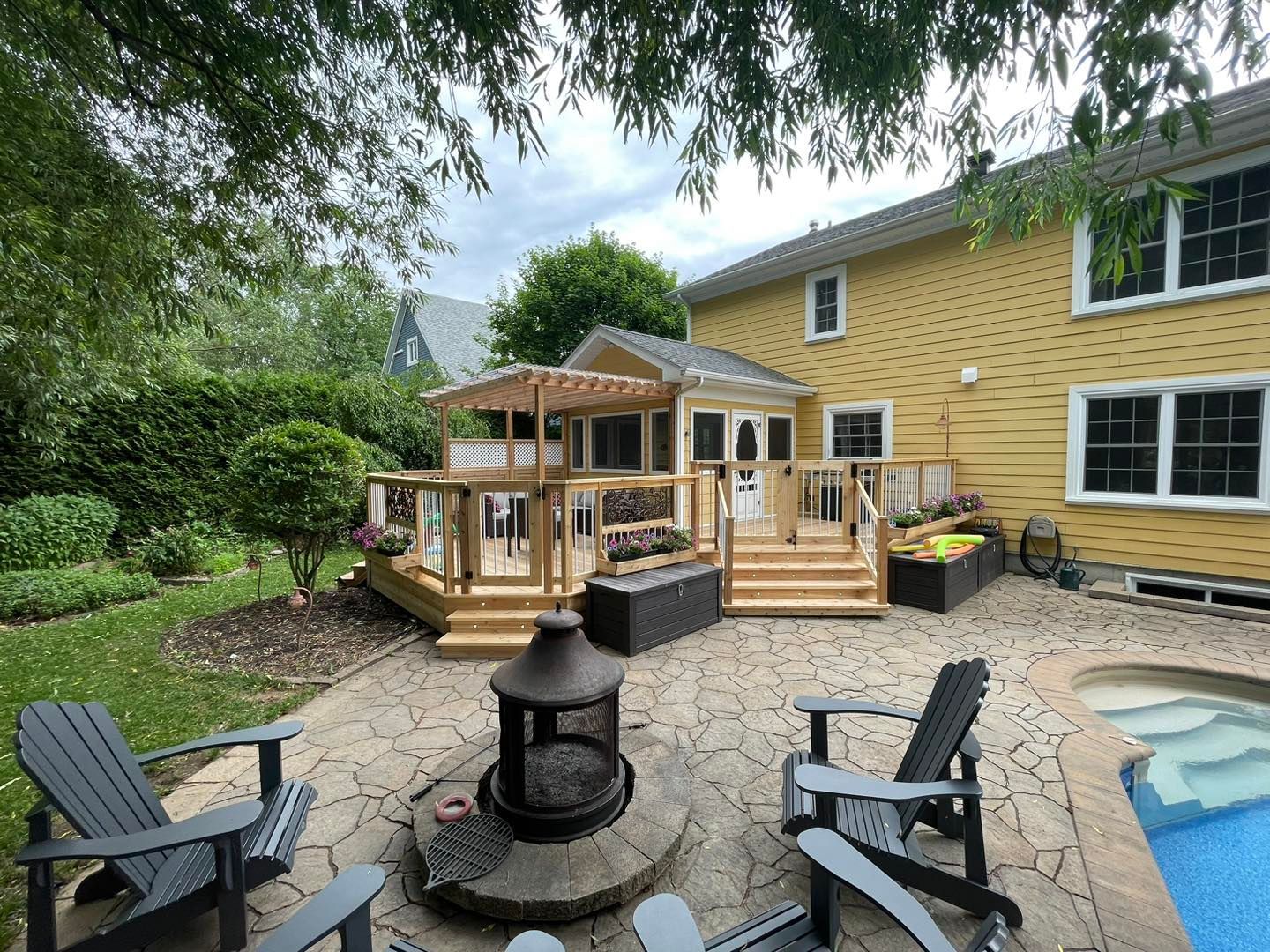 Un patio avec des chaises et un foyer devant une maison.