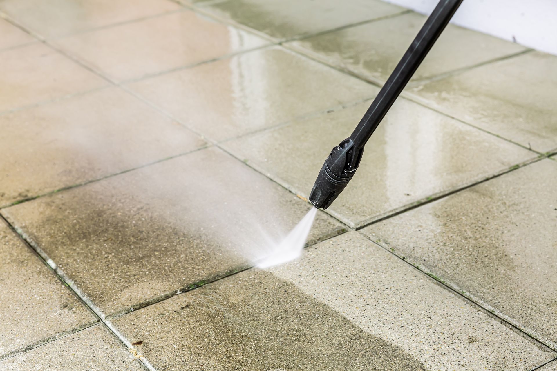 a person is cleaning the side of a house with a high pressure washer .