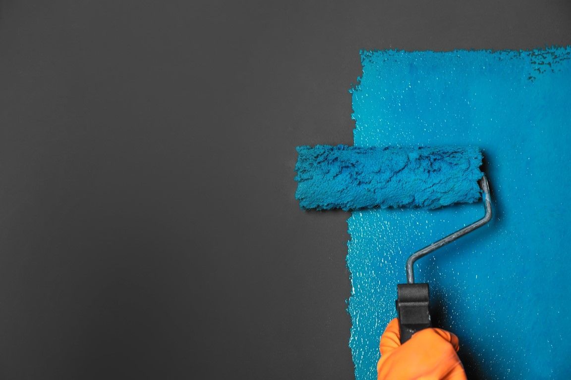 up close picture of a paint roller painting a wall blue