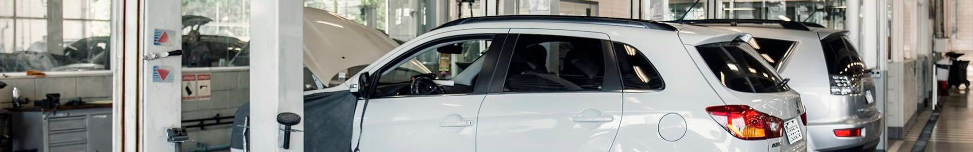 SUVs brancas dentro de uma oficina mecânica.