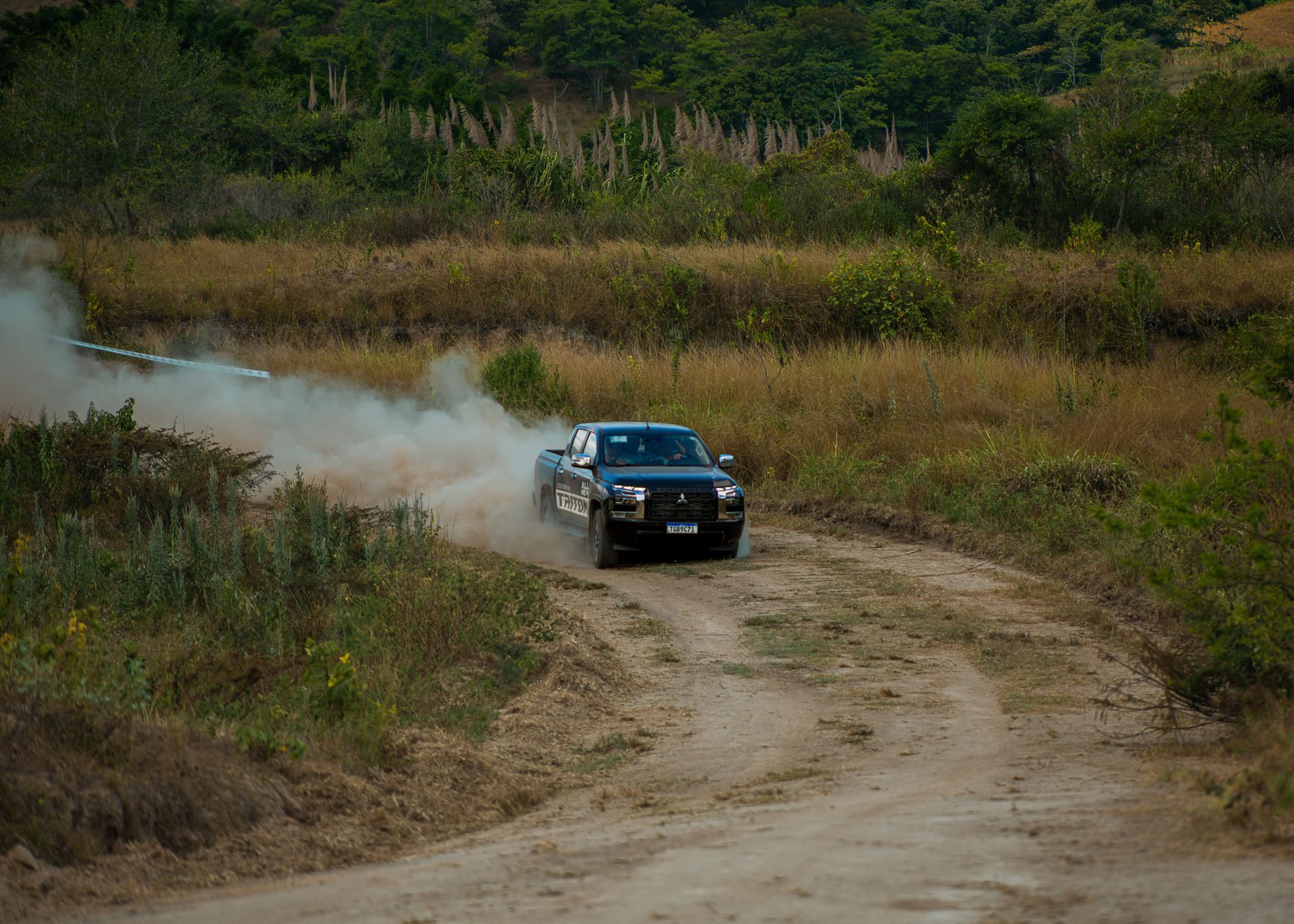 Uma caminhonete preta trafegando em alta velocidade por uma estrada de terra