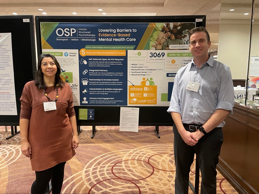 two people standing in front of a sign that says lowering barriers to evidence-based mental health care