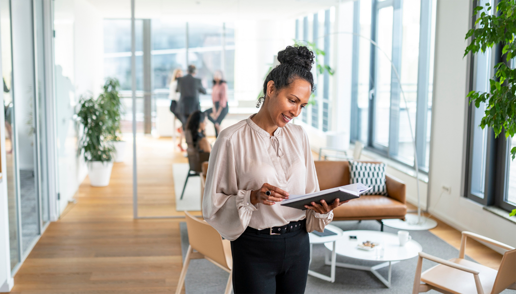 A happy and productive employee reading while standing in the middle of a clean and organized office