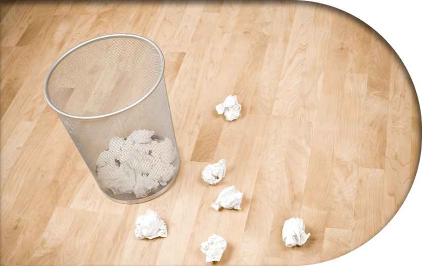 A trash bin with crumpled paper in and surrounding it