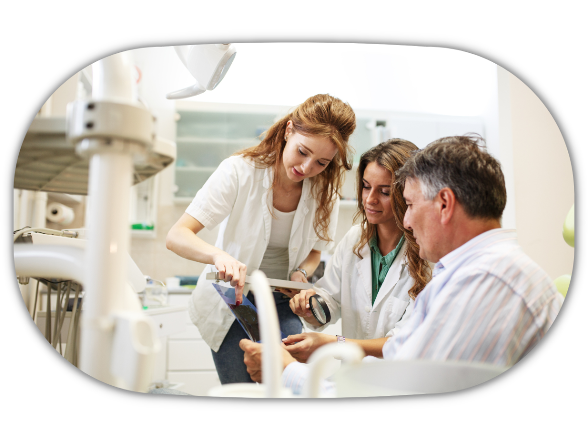 dentist and her assistant in dental office talking to senior patient