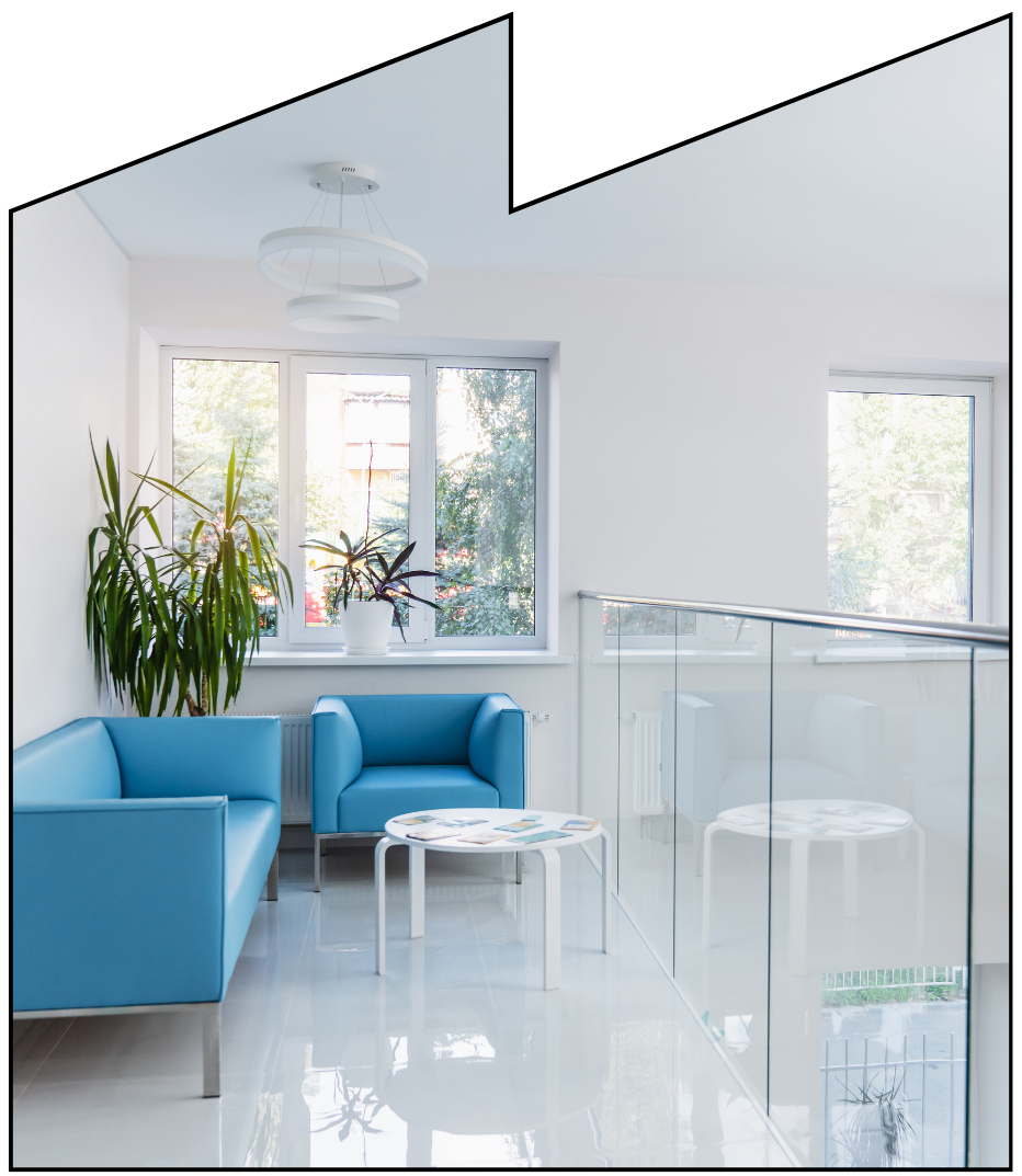 A dental clinic waiting room with a blue couch and a blue chair.
