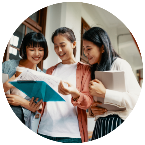 Three women students huddled together and examining a blue folder. Their focused expressions suggest that the contents of the folder are of utmost importance.