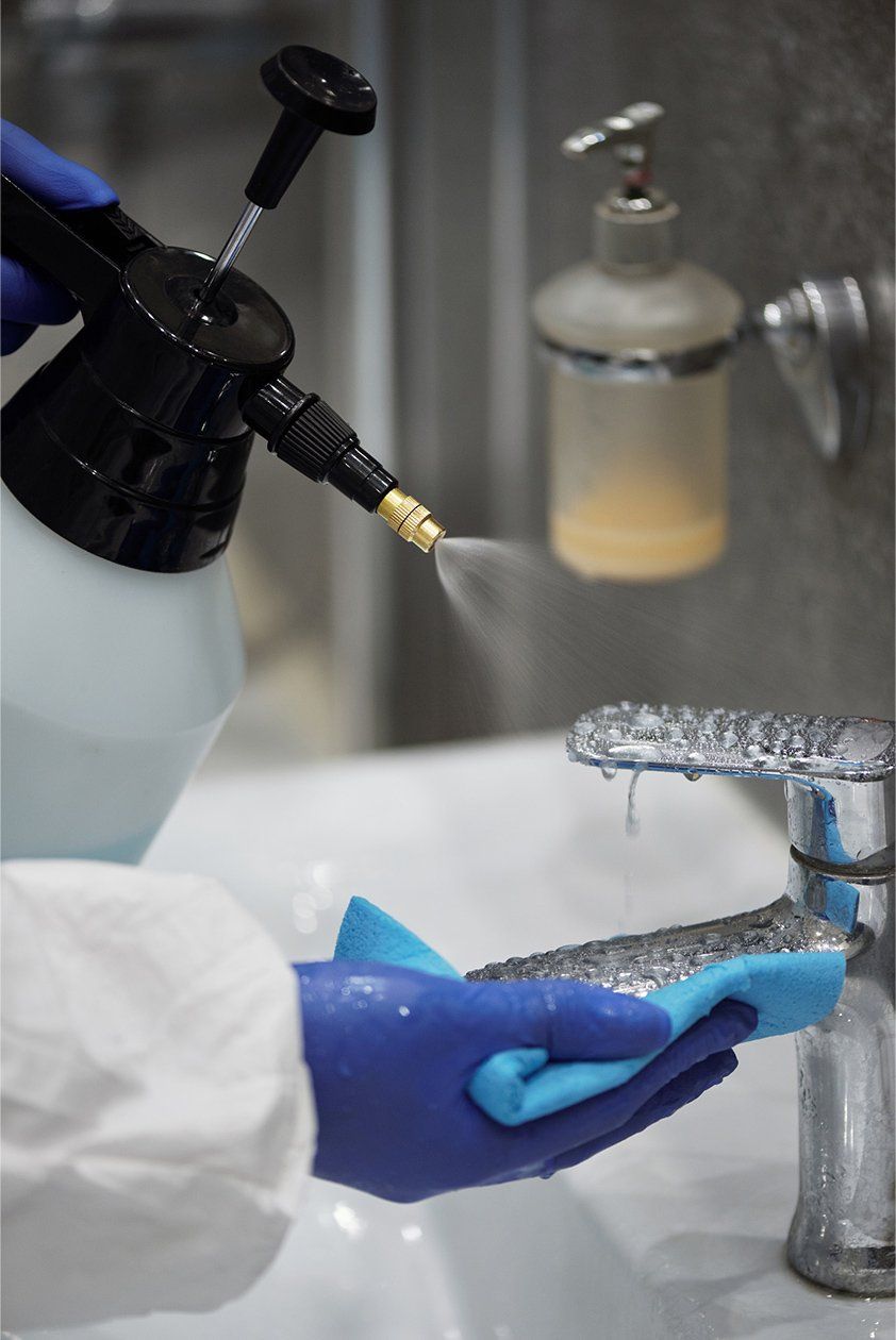 Gloved Hands using a spray bottle to clean a public bathroom