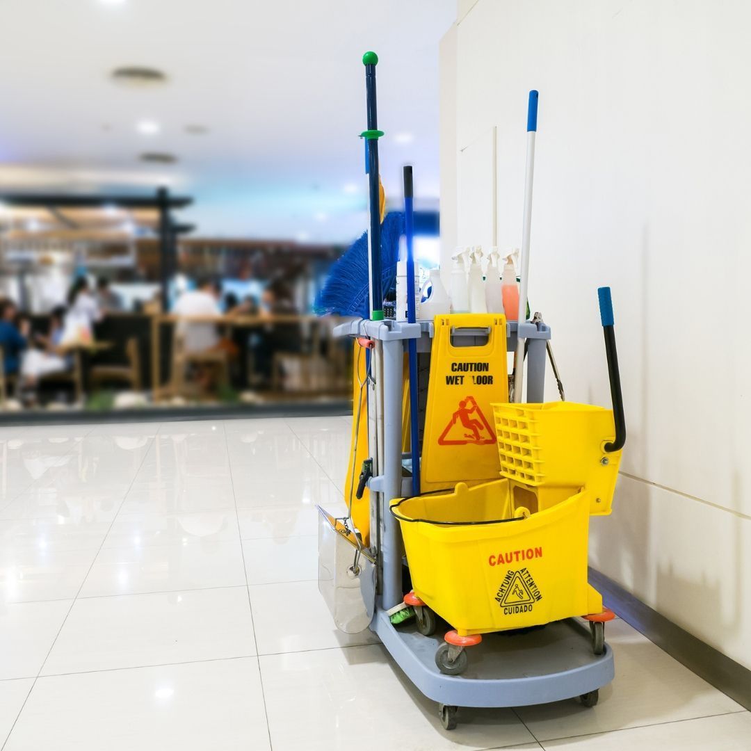 A yellow mop cart with a caution sign on it
