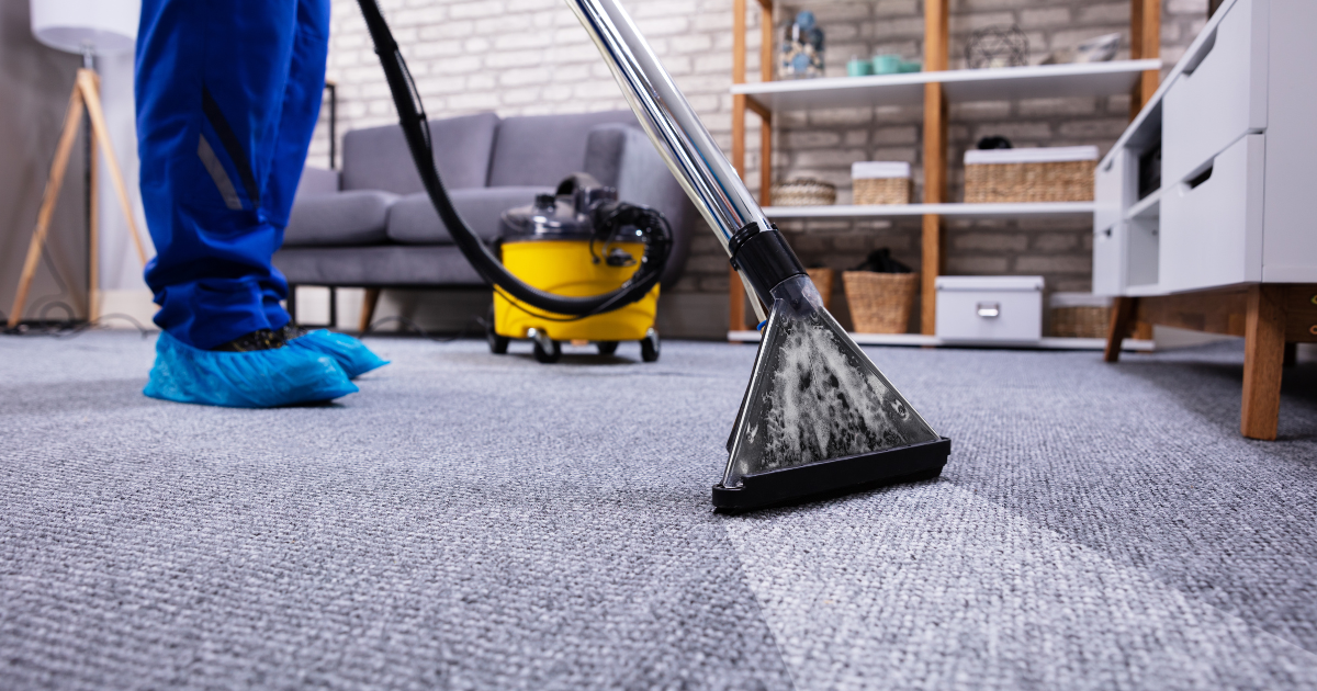 A person is cleaning a carpet with a vacuum cleaner in a living room.
